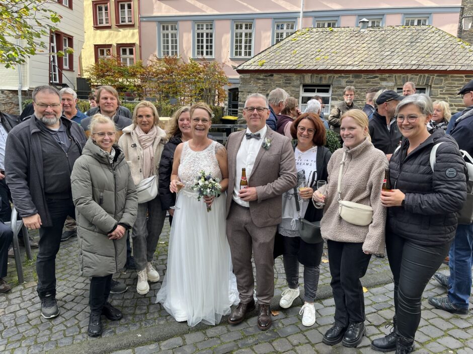 Ein Brautpaar steht umringt von Gratulanten.