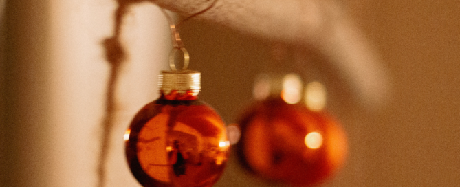 Zwei Weihnachtskugel hängen an einem Holzstock.