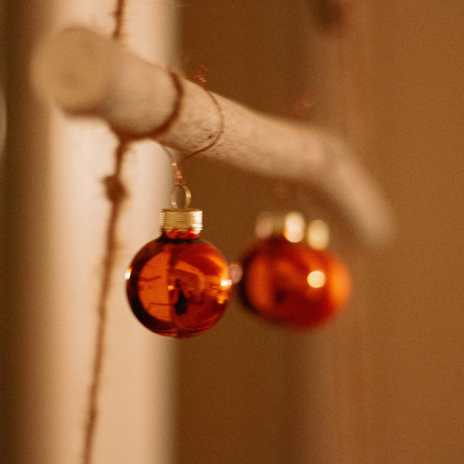 Zwei Weihnachtskugel hängen an einem Holzstock.