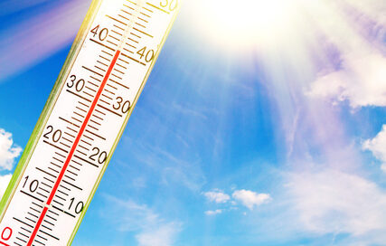 Ein Thermometer vor einem blauen Himmel mit Sonnenschein.