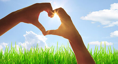 Zwei Hände bilden ein Herz vor blauem Himmel