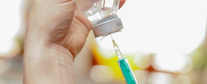 Eine Spritze wird an einer Ampulle aufgezogen.