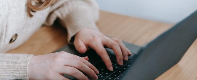 Zwei Hände einer Frau tippen auf der Tastatur eines Laptops.