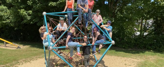 Menschen posieren auf einem Seilspielgerät auf einem Spielplatz.